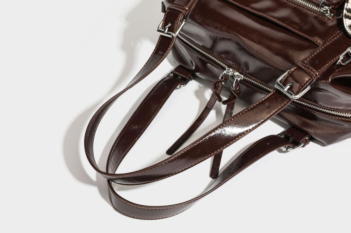 Strukturierte Schultertasche in glänzender Lederoptik mit abgerundetem Korpus, silberfarbenen Beschlägen, Reißverschlussfach auf der Vorderseite und Leopardenmuster