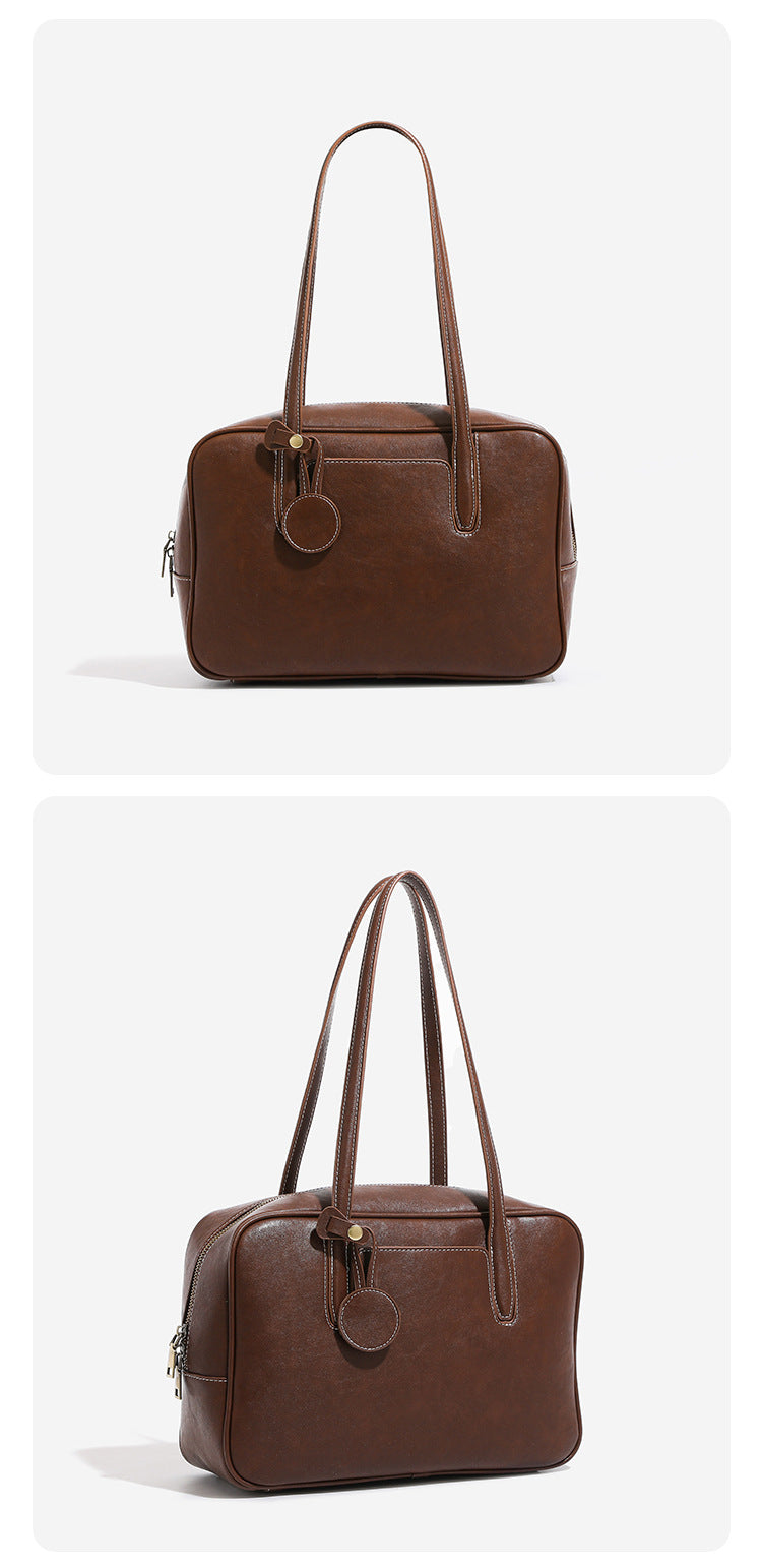 Structured boxy bowling-style tote bag in deep brown leather-look finish with dual top handles, front slip pocket, round
