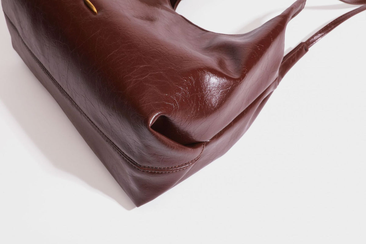 Locker fallende Hobo-Schultertasche mit offenem Oberteil aus glänzendem, geknautschtem Lederimitat in Dunkelbraun, mit schmalem verstellbarem Riemen und goldfarbenem