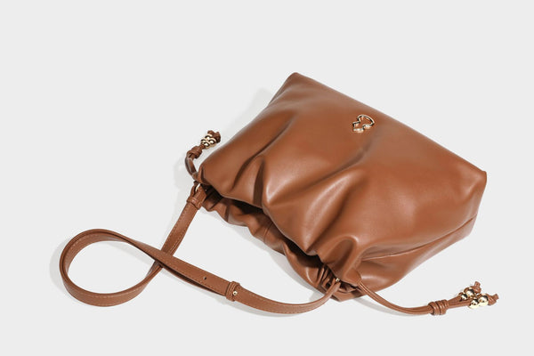Slouchy ruched drawstring shoulder bag in smooth leather-look finish with gold-tone emblem and slim adjustable strap, detail