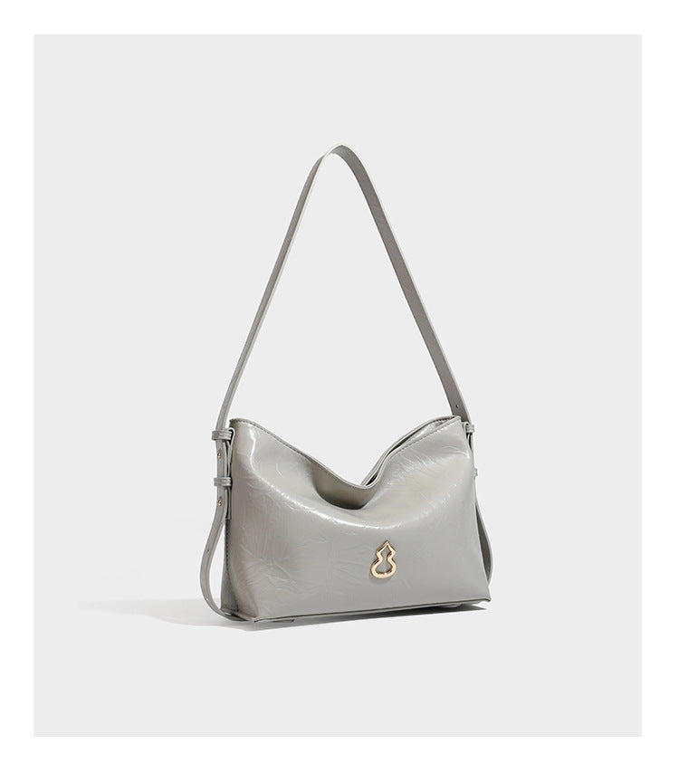Lässige Hobo-Schultertasche mit offenem oberen Abschluss in glänzender karamellfarbener Lederoptik mit goldfarbenen Logo-Beschlägen und langem, verstellbarem