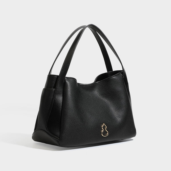 Schwarze Tote-Bag in genarbter Lederoptik mit kürbisförmigen Beschlägen in Goldoptik, zwei Tragegriffen und abnehmbarem Crossbody-Schulterriemen, Detailansicht