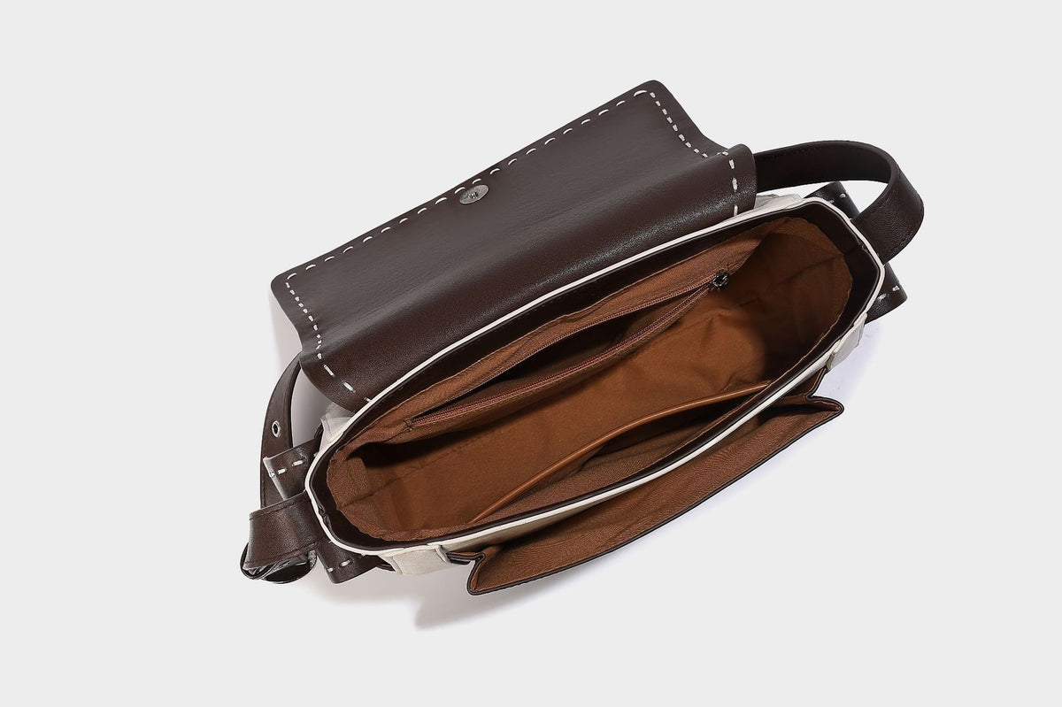 Structured flap crossbody bag in dark brown and cream color-block with white contrast stitching, adjustable shoulder strap