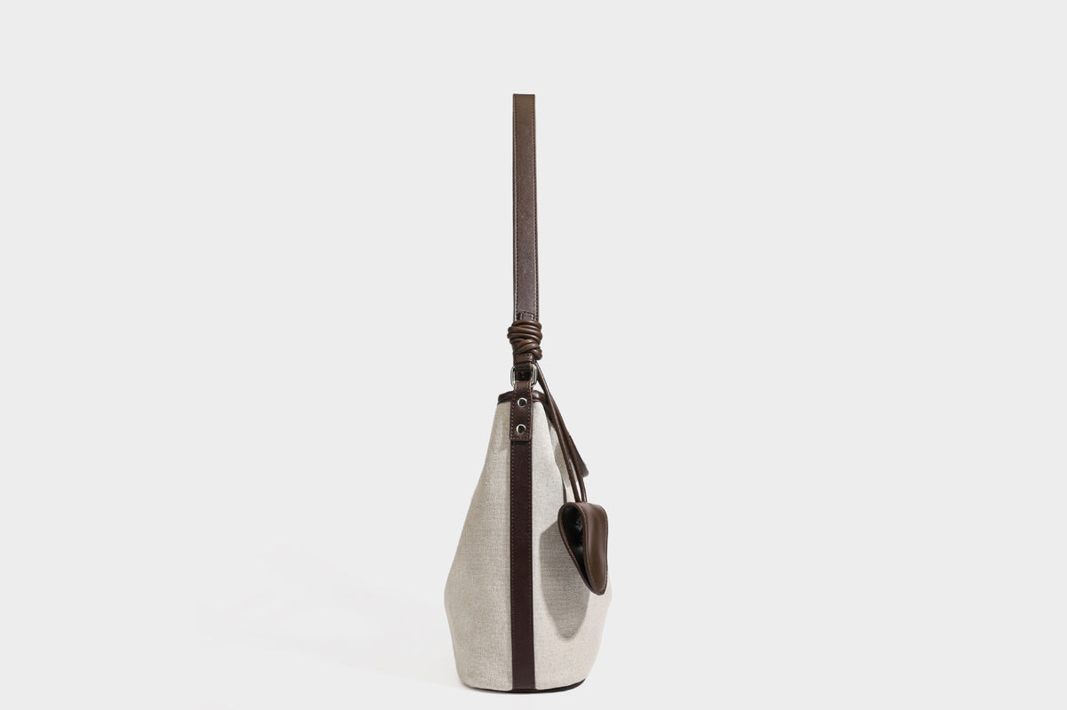 Oatfarbene Canvas-Schultertasche mit dunkelbraunem Besatz in Lederoptik, langem verstellbarem Riemen und angebrachter Mini-Tasche mit Überschlag, Detailansicht