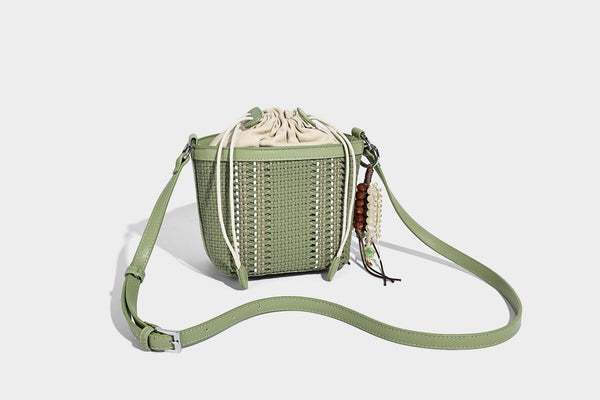Small woven bucket bag with drawstring top, braided handle, detachable crossbody strap, and silver-tone ring hardware, detail
