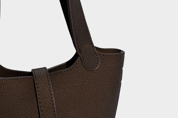 Kleine matte Beuteltasche mit genarbter Oberfläche, antikgoldfarbenen Ringbeschlägen, Perlen- und Quastenanhänger, kurzen Tragegriffen oben und
