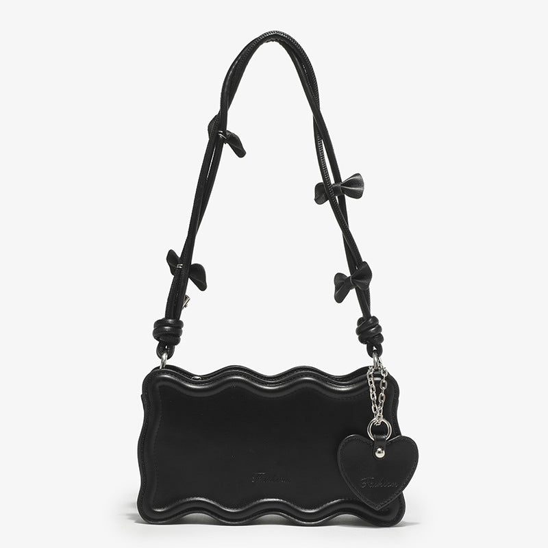 Small structured scalloped-edge shoulder bag with bow-tied pink cord strap and silver heart charm pendant, detail view 8