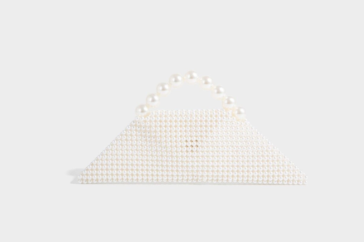 Small structured triangle clutch bag covered in glossy pearl beads with an arched pearl top handle and silver snap closure