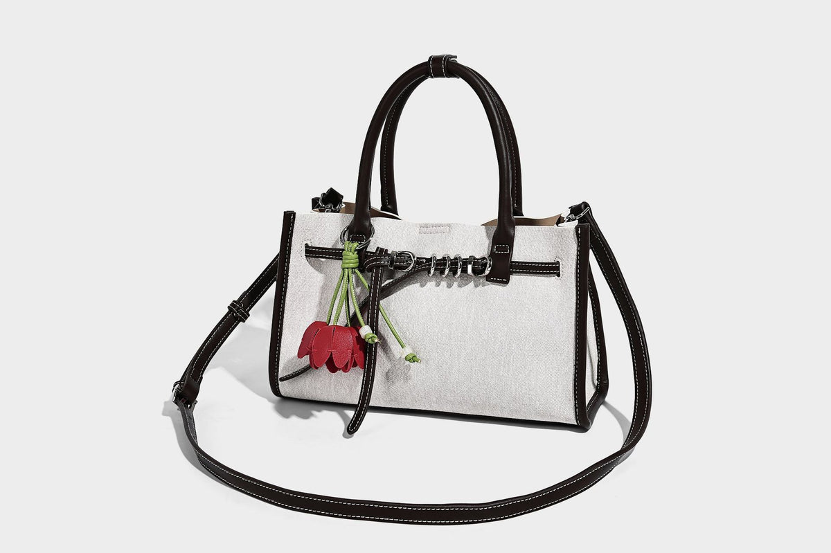 Structured rectangular tote satchel in denim-look fabric with dark trim, knotted front strap hardware, and detachable, detail