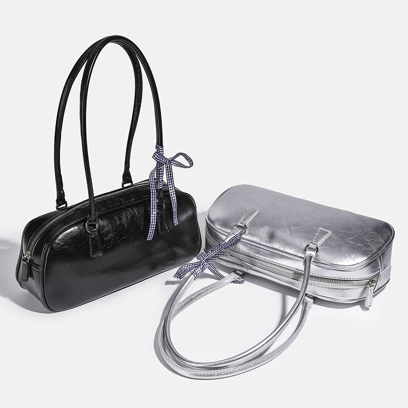 Rounded rectangular shoulder bag with glossy crinkled finish, dual long handles, top zip closure, and gingham ribbon bow
