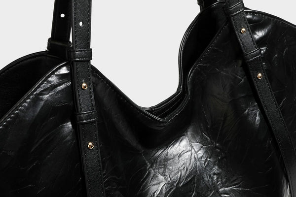 Große, glänzende Tote-Bag aus schwarzem Lederimitat mit geknitterter Optik, lässig fallender Trapezsilhouette, zwei Schulterriemen und goldfarbenen