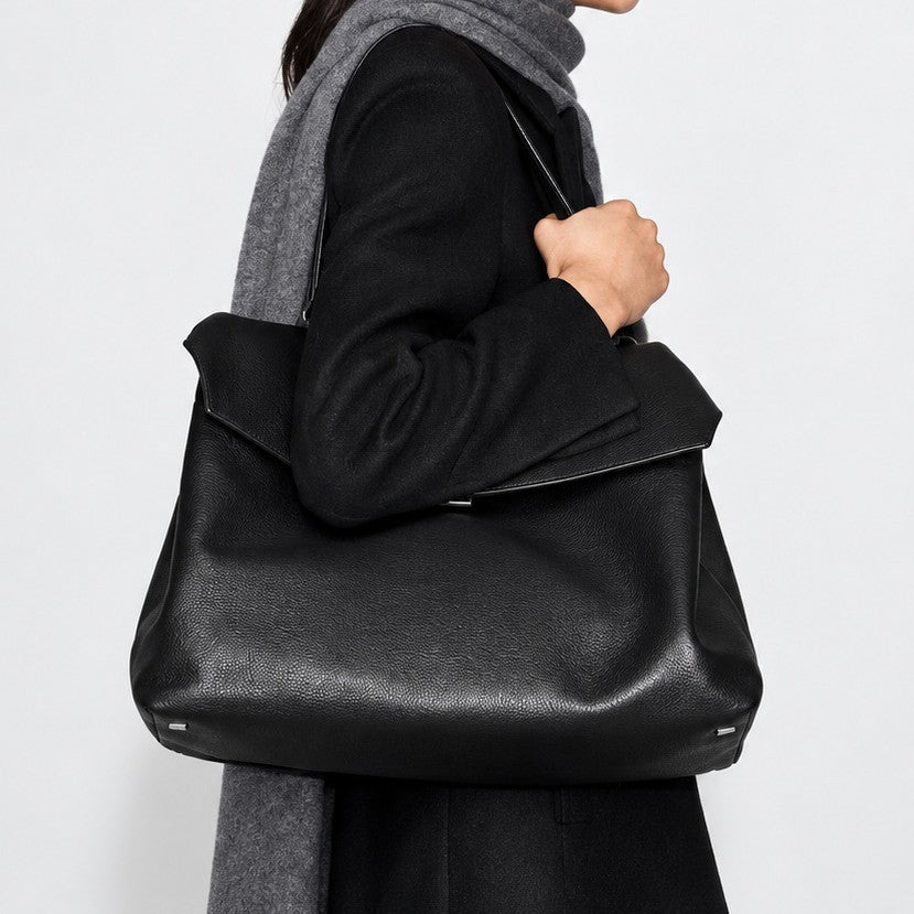 Large black slouchy leather-look shoulder bag with V-shaped envelope flap, silver-tone clasp, and adjustable strap, detail
