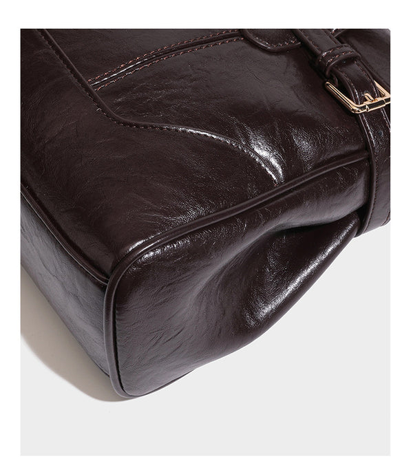 Structured glossy leather-look satchel bag with flap closure, gold-tone buckle accents, double top handles, detachable