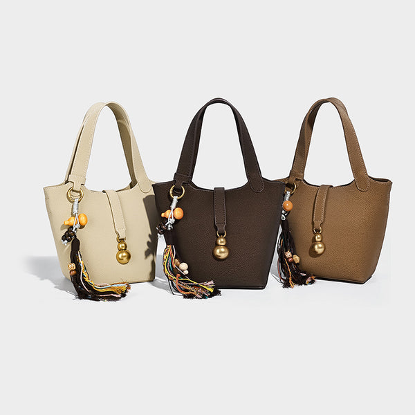 Kleine Beuteltasche mit genarbter, matter Oberfläche, antikgoldfarbenen Ringbeschlägen, Perlen- und Quastenanhänger, kurzen Henkeln und