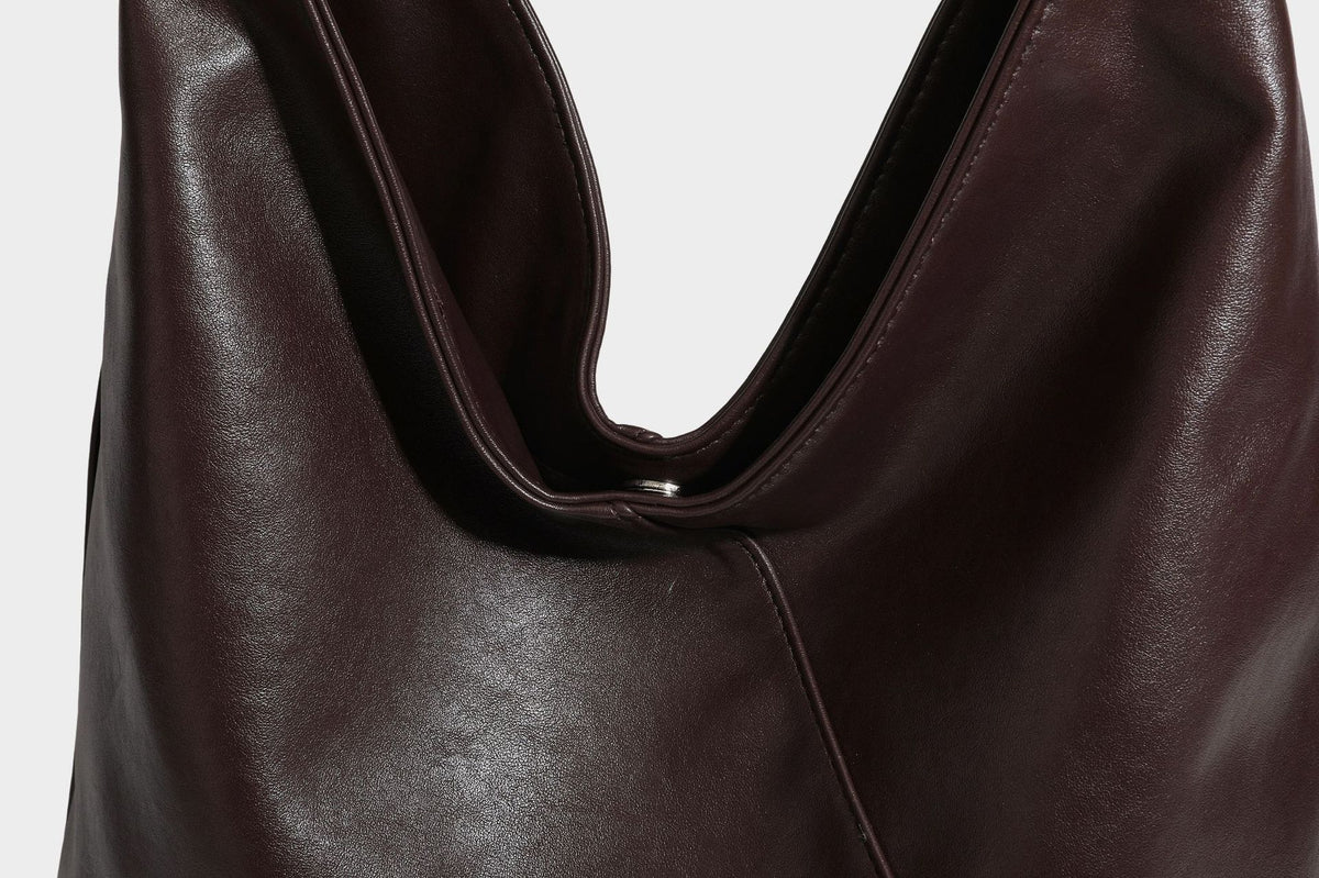 Large slouchy hobo shoulder bag with braided top handle, smooth glossy leather-look finish, and silver-tone ring hardware