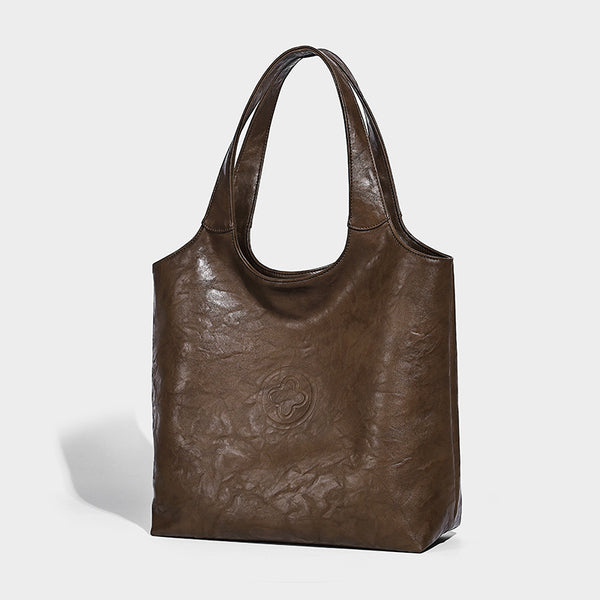 Large open-top tote bag with crinkled leather-look finish, long double shoulder straps, and embossed circular detail on