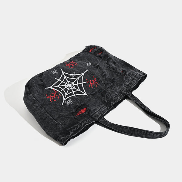 Large washed black distressed denim tote bag with white spider web embroidery and red spider motifs on the front panel