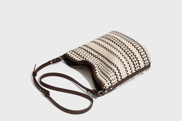 Woven stripe bucket shoulder bag in cream and dark brown with leather-look trim, knotted adjustable strap, and small shield