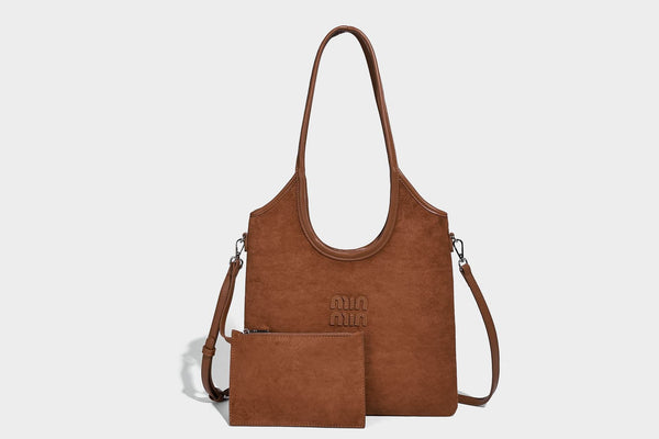 Tote-Bag in warmem Braun mit matter Wildlederoptik, langen Tragegriffen, geprägtem Logo, silberfarbenen Beschlägen und passendem, Detail