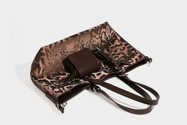 Glossy leopard-print tote bag with leather-look dark trim, dual top handles, detachable shoulder strap, and attached front