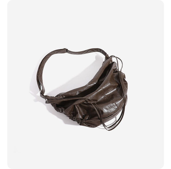 Oversized slouchy hobo shoulder bag with glossy crinkled leather-look finish, drawstring gathered sides, and silver-tone