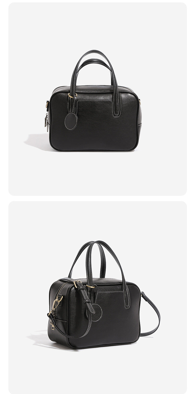 Structured boxy bowling-style tote bag in deep brown leather-look finish with dual top handles, front slip pocket, round