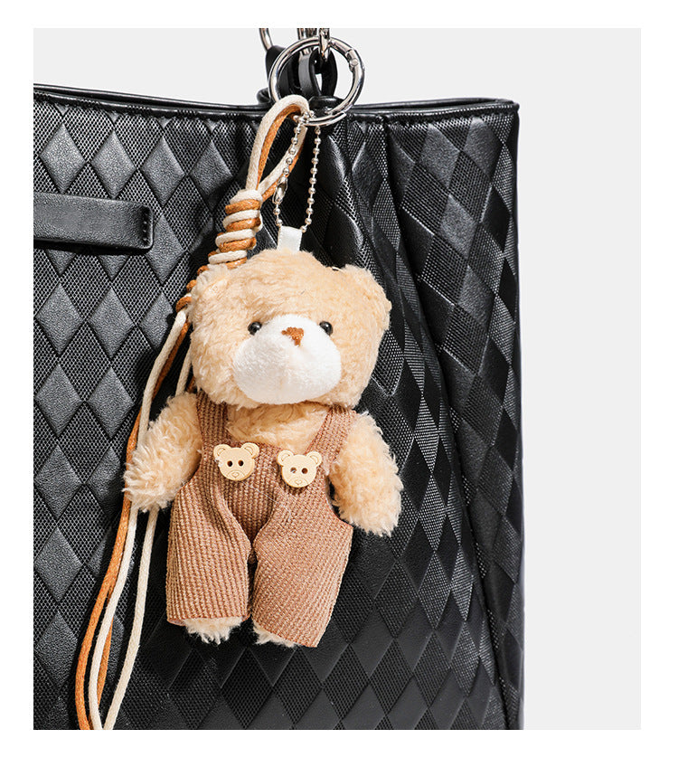 Black diamond-quilted leather-look tote bag with silver chain-ring shoulder straps and plush bear charm pendant, detail view