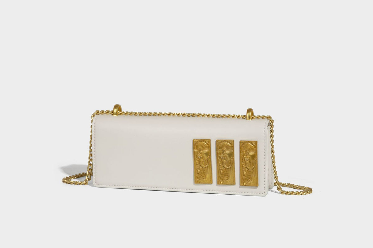 Structured rectangular crossbody bag with glossy finish, three vertical gold-tone embossed plaques, and gold chain strap