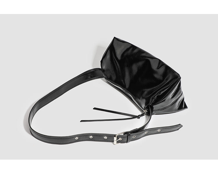 Black glossy leather-look slouchy shoulder bag with gathered top, zip tassel closure, and long adjustable silver-buckle