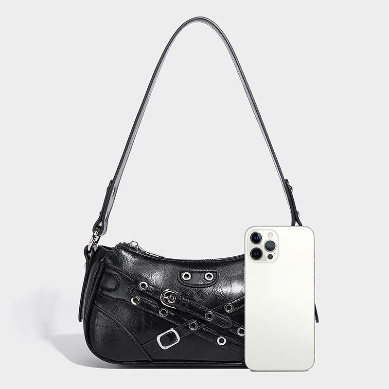 Compact moto-inspired shoulder bag with crisscross grommet strap detail, glossy textured finish, and adjustable crossbody