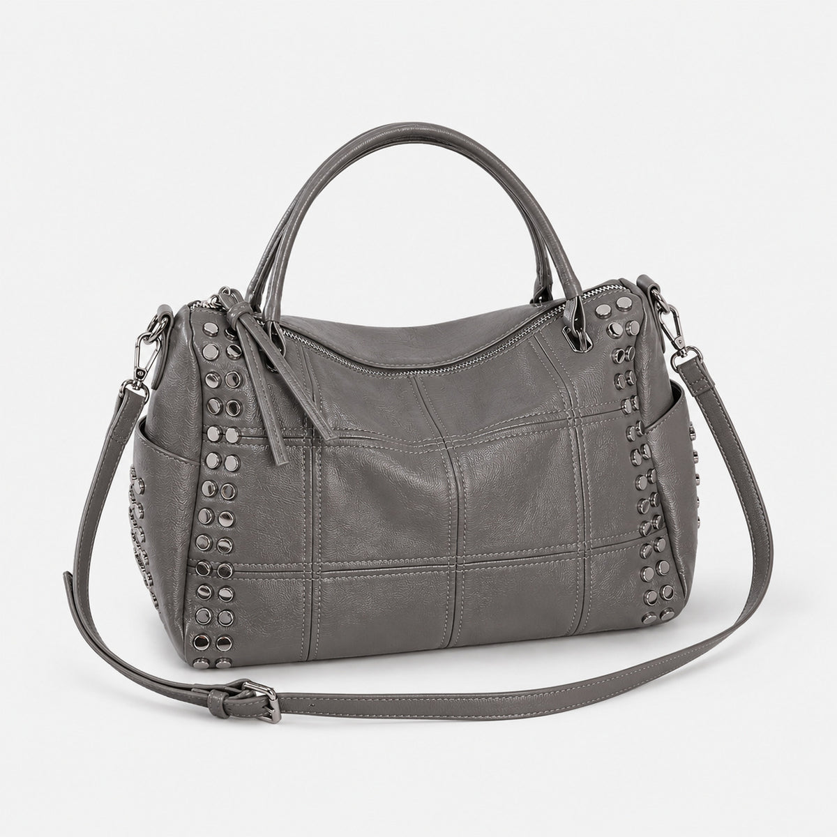 Black leather-look satchel bag with gunmetal rivet trim, grid-stitched paneling, dual rolled top handles, and curved zip