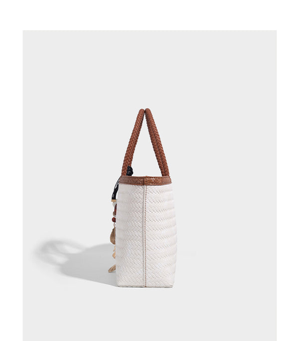 Structured woven-texture tote bag with brown braided top handles, decorative tassel charm, and detachable shoulder strap
