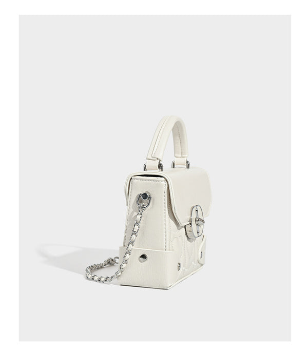 Kleine strukturierte Box-Tasche aus herzförmig gestepptem PU mit Henkel, silberfarbenem Kettenriemen zum Tragen als Crossbody und ovalem Drehverschluss, Detailansicht