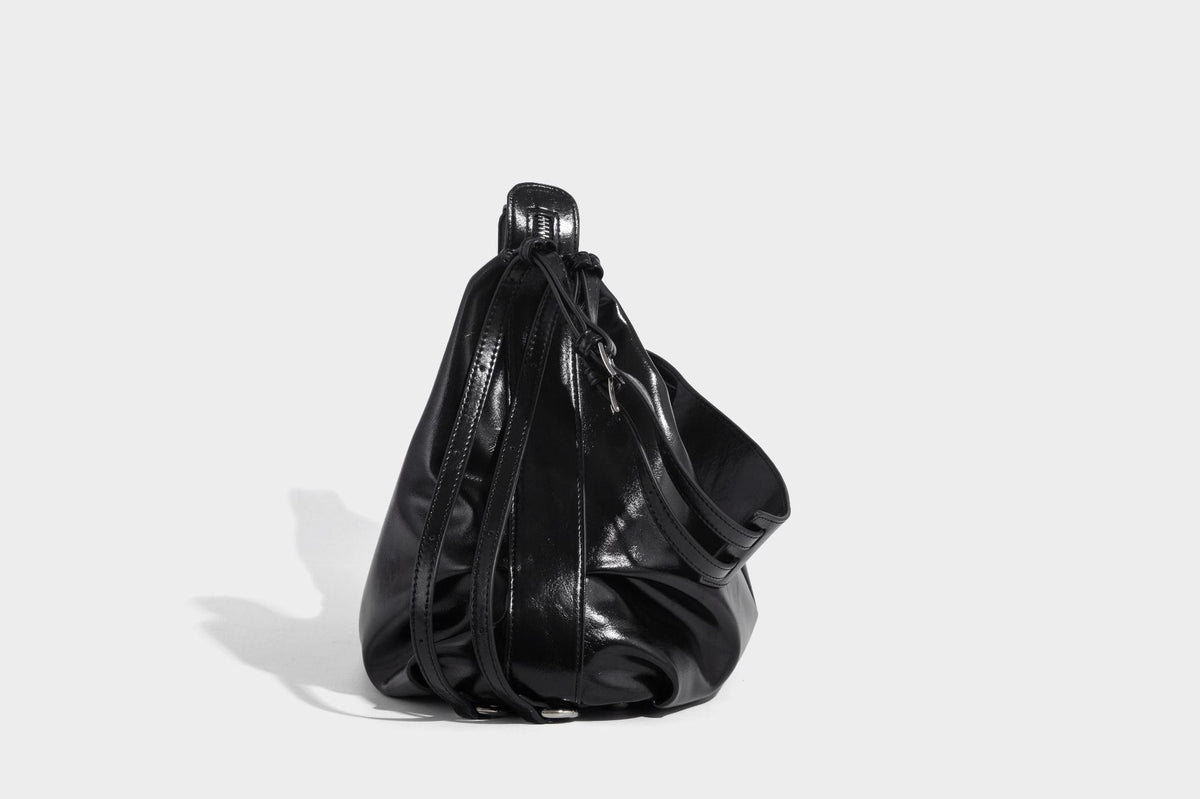 Glossy black slouchy hobo shoulder bag with zip closure, silver-tone ring hardware, and adjustable crossbody strap, detail