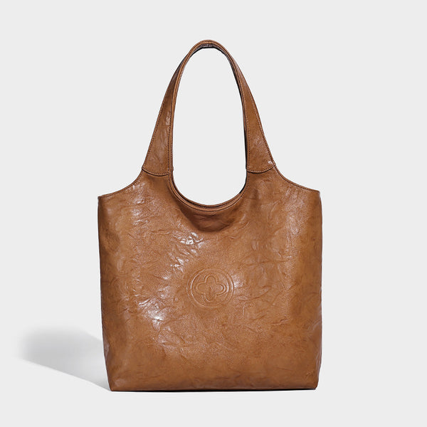 Large open-top tote bag with crinkled leather-look finish, long double shoulder straps, and embossed circular detail on