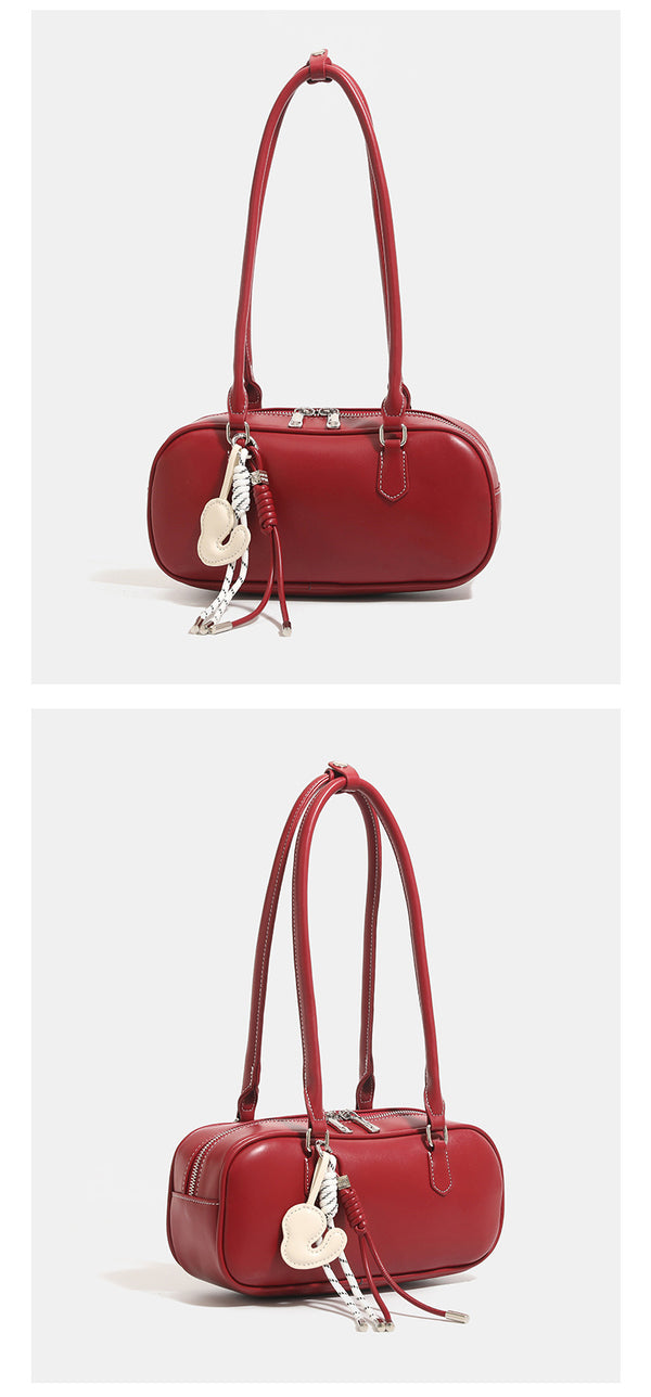 Compact rounded baguette shoulder bag with smooth leather-look finish, slim double straps, silver-tone zipper hardware, and
