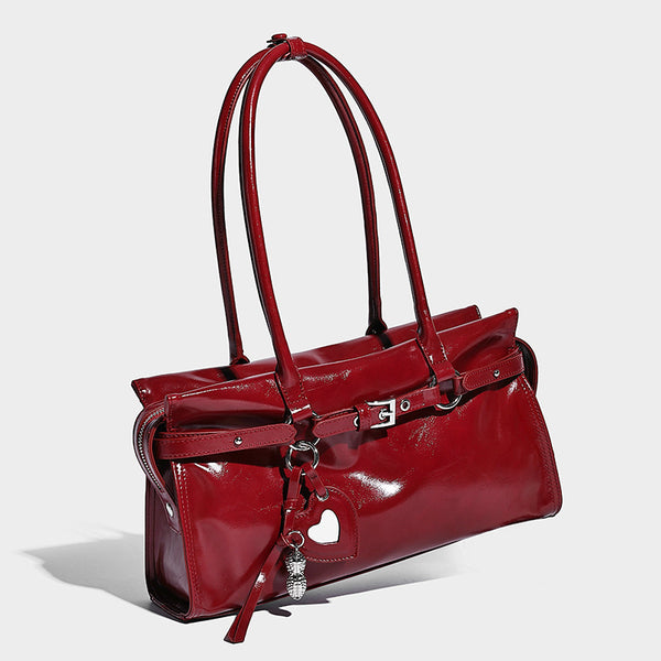 Structured rectangular glossy tote shoulder bag with belt buckle front strap and dangling charm hardware, front view