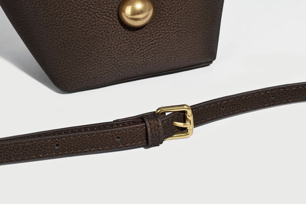 Kleine matte Beuteltasche mit genarbter Oberfläche, antikgoldfarbenen Ringbeschlägen, Perlen- und Quastenanhänger, kurzen Tragegriffen oben und
