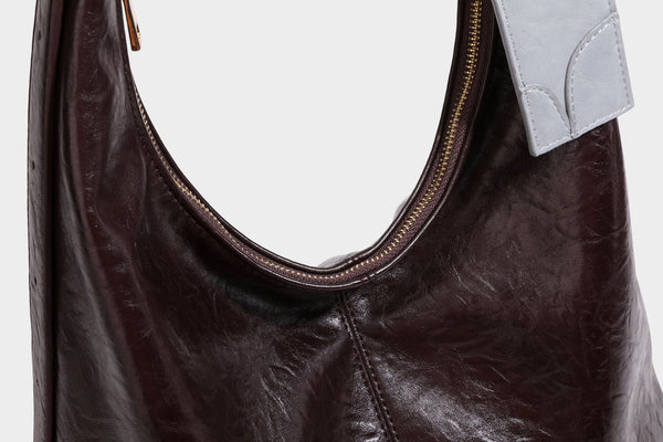 Große dunkelbraune, glänzende, geknautschte Hobo-Schultertasche mit Reißverschluss, goldfarbenen Metalldetails, verstellbarem Trageriemen und Hellblau