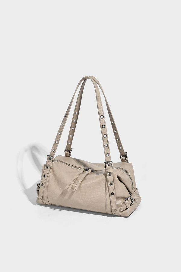 Pale yellow leather-look barrel bag with silver grommet-studded shoulder straps, top zip closure, and pink tulip floral
