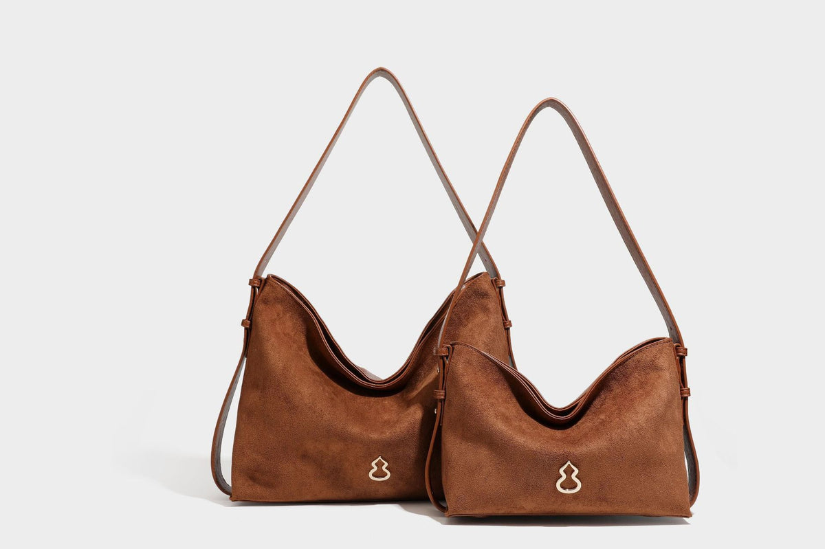 Slouchy suede-finish brown shoulder bag with long single strap and small gold-tone logo emblem on front, detail view 27