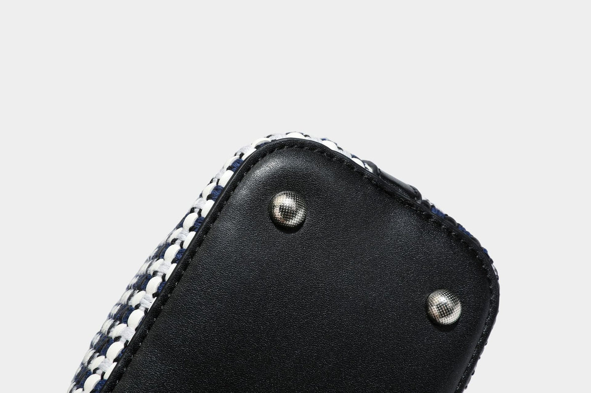 Small structured woven checker bucket bag with braided top handle, drawstring closure, and silver-tone hardware in black