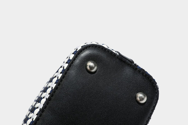 Small structured woven checker bucket bag with braided top handle, drawstring closure, and silver-tone hardware in black