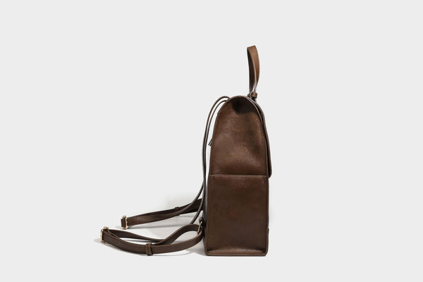 Structured suede-look convertible backpack handbag with flap closure and gold-tone emblem hardware in chocolate brown, detail