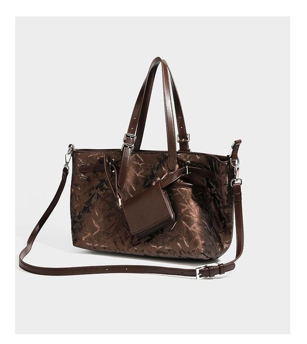 Glossy crinkled metallic-finish tote bag in brown with smooth leather-look top handles, silver-tone hardware, and attached