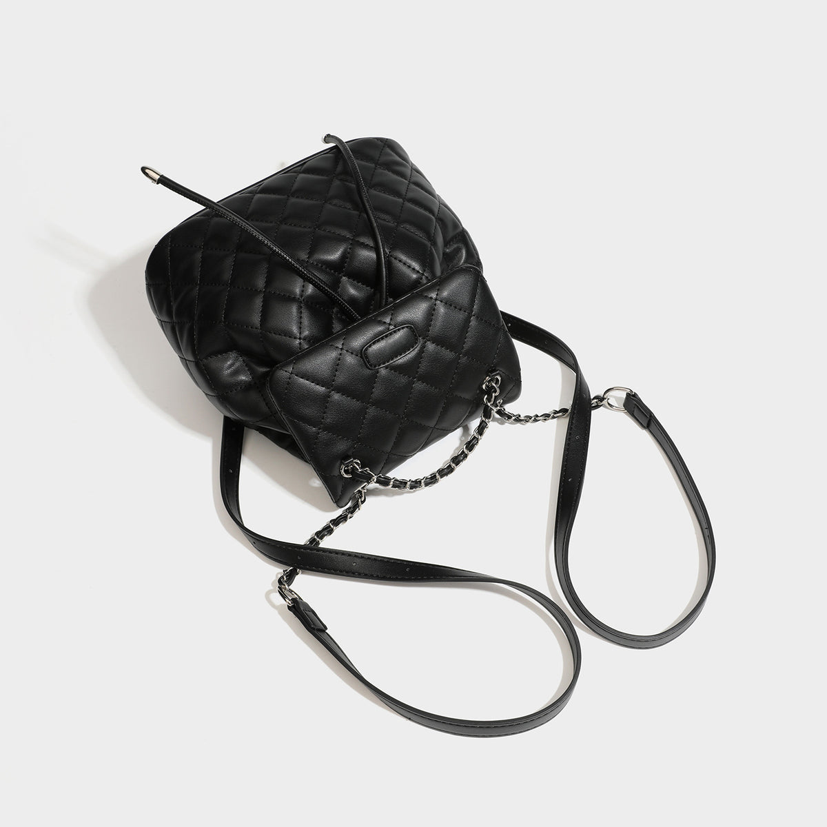 Black diamond-quilted backpack handbag with silver-tone chain flap accent and adjustable shoulder straps, detail view 4