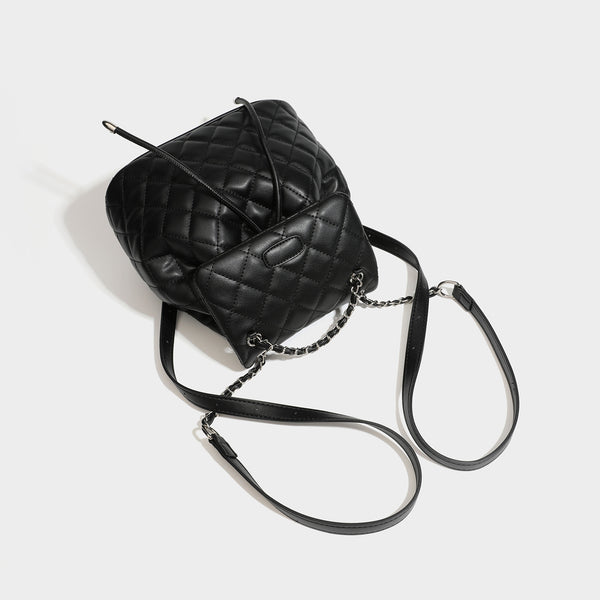 Black diamond-quilted backpack handbag with silver-tone chain flap accent and adjustable shoulder straps, detail view 4
