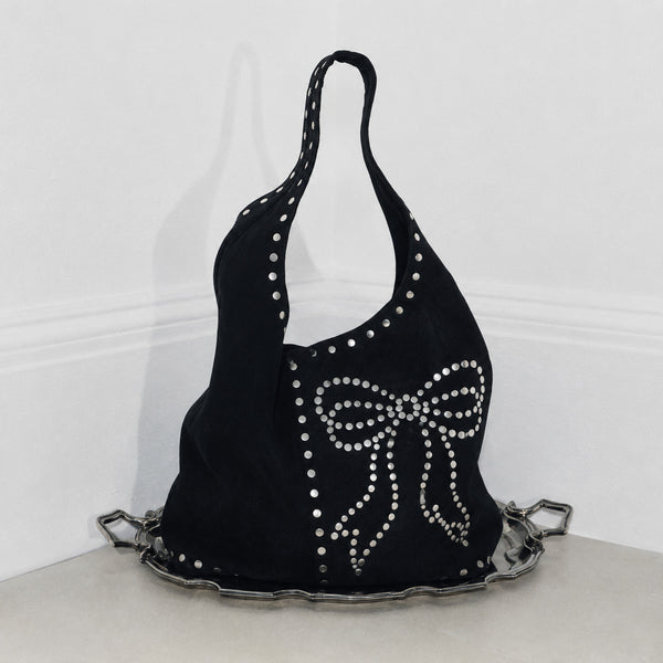 Oversize-Hobo-Schultertasche in schwarzer Velourslederoptik mit silberfarbenen Rundnieten und großem, mit Nieten besetztem Schleifenmotiv auf der Vorderseite, Detailansicht