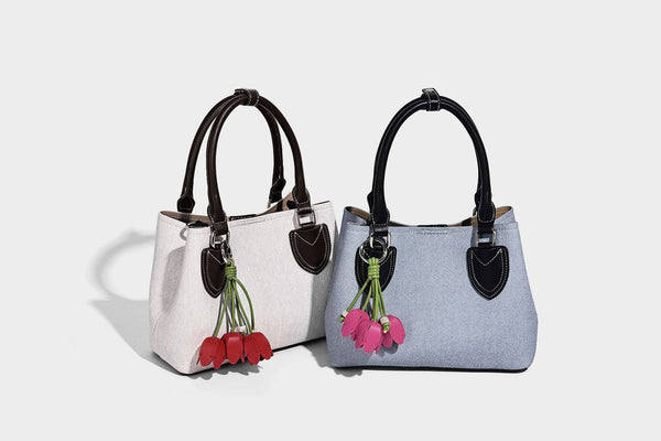 Structured light-blue denim-look tote bag with black leather-look handles, white contrast stitching, silver-tone hardware