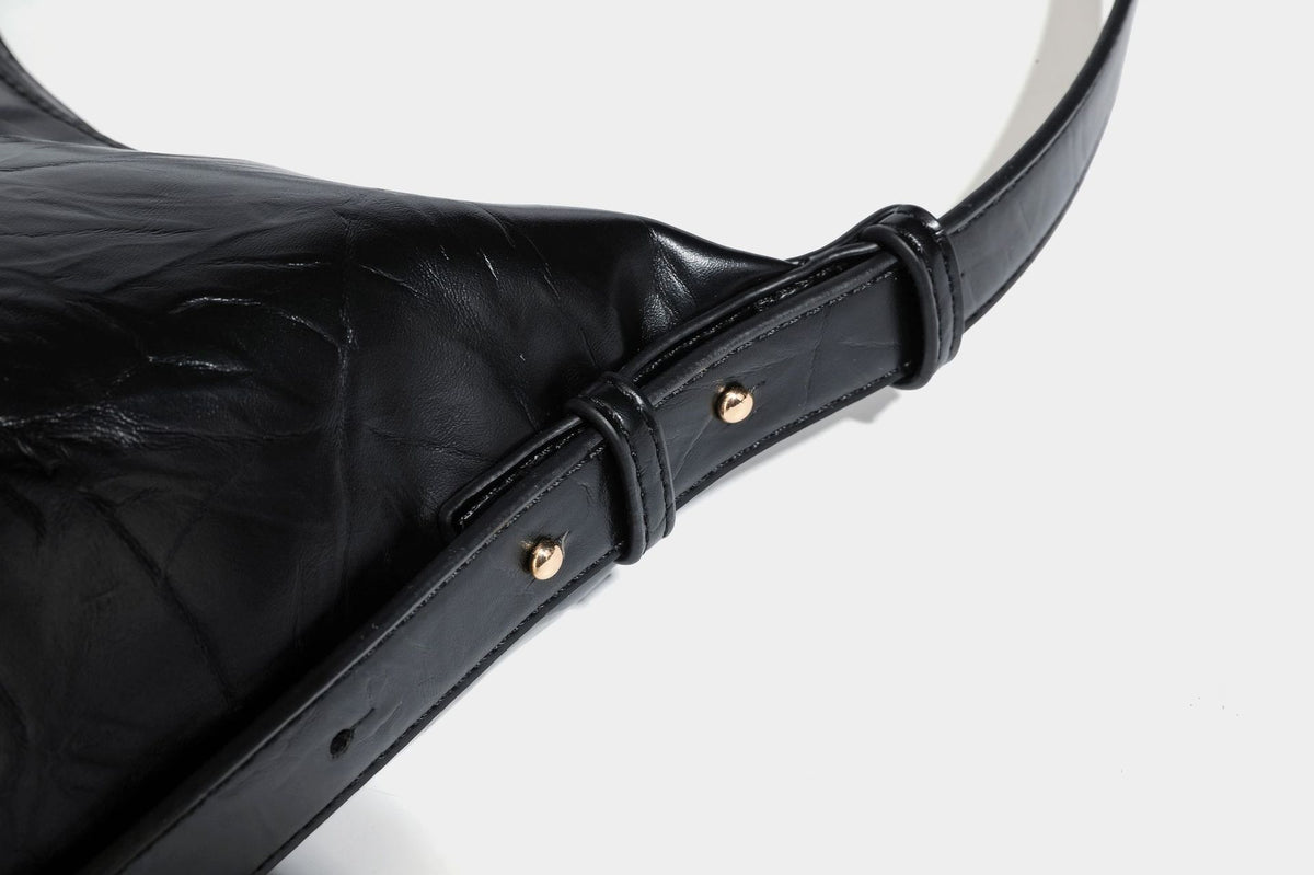 Übergroße, lässig fallende Hobo-Schultertasche aus glänzendem, geknittertem Lederimitat mit goldfarbenem Reißverschluss und Emblem-Beschlägen, Detailansicht